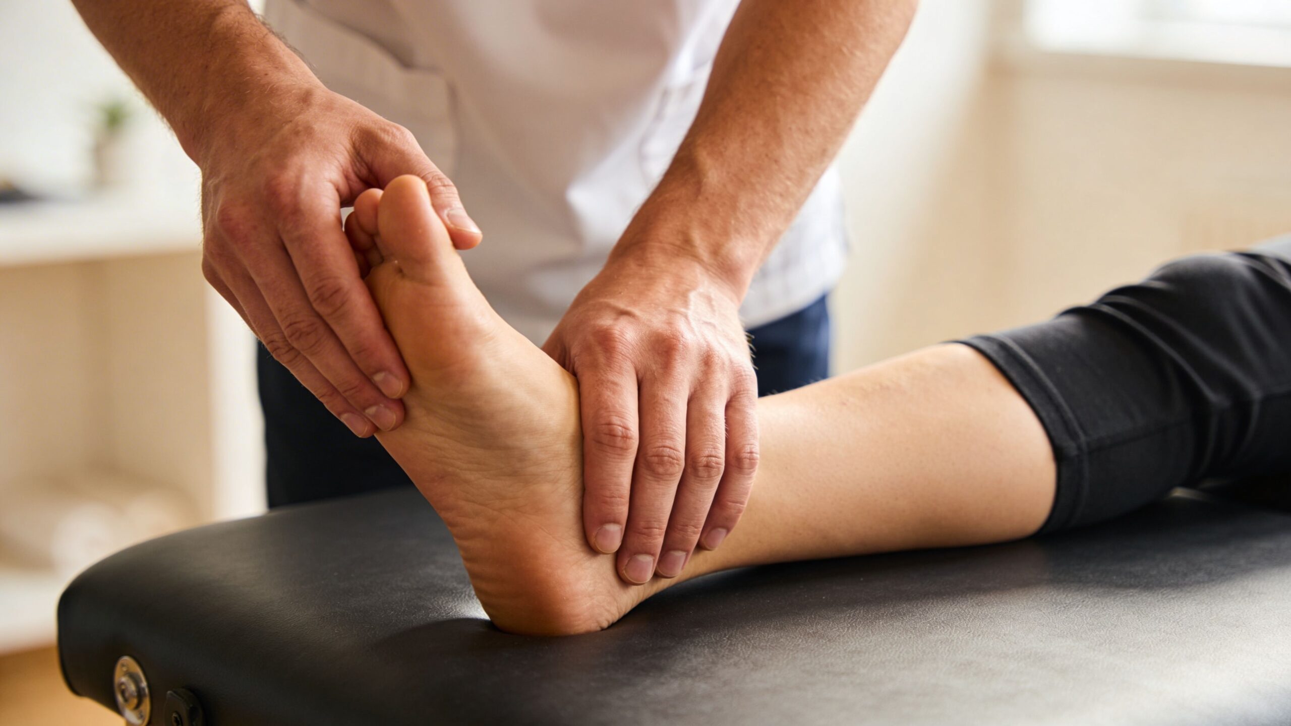 A professional physical therapist performing an examination on a patient's foot and ankle during a therapy session.