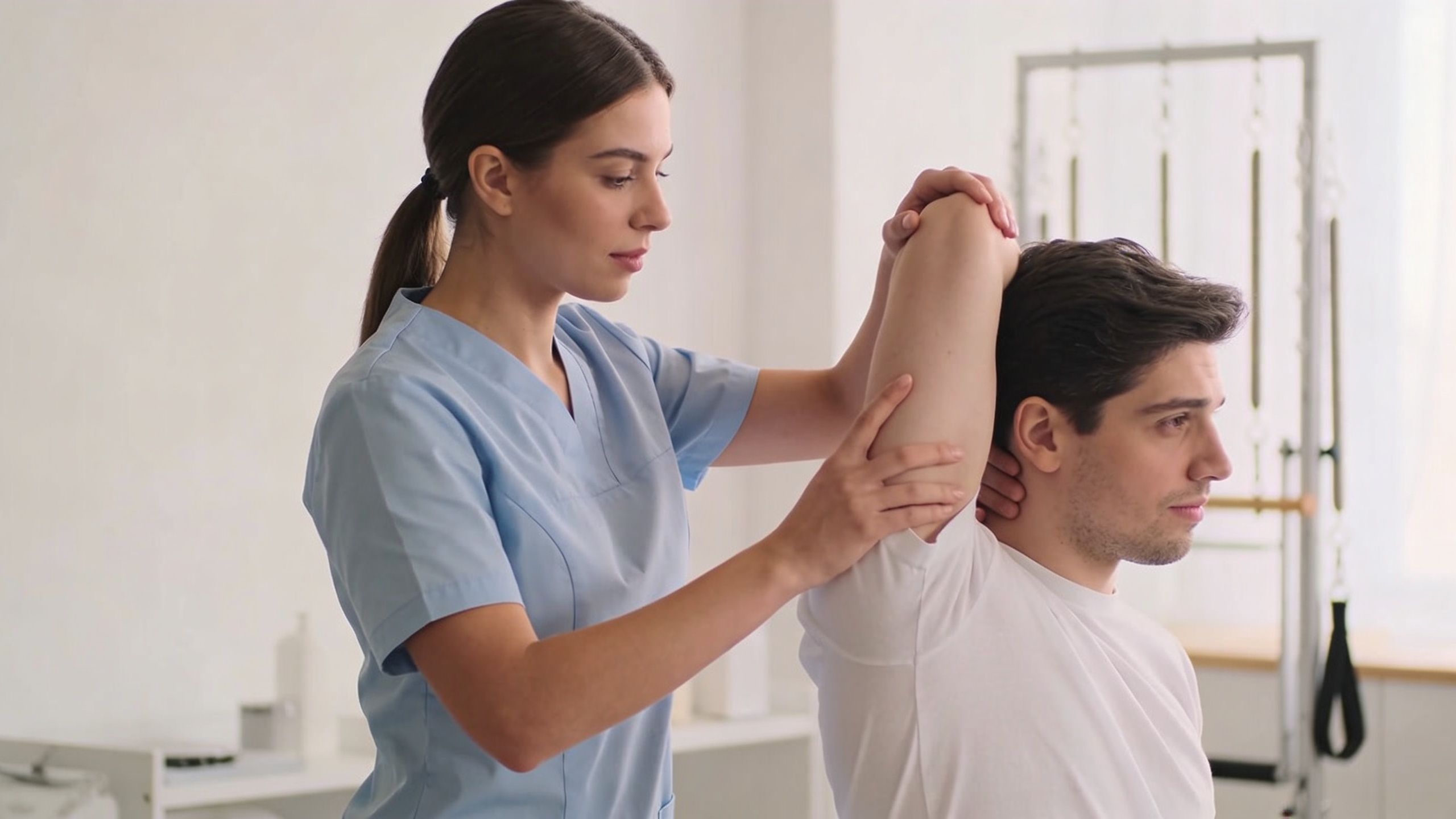 A female physical therapist providing manual shoulder stretching to a male patient in a clinical setting.